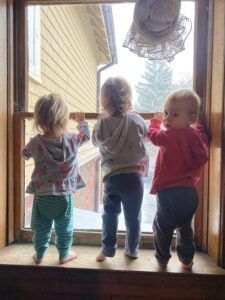 Triplets looking at window with one looking at camera