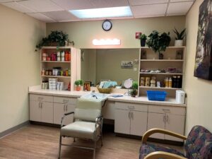 Clean and aesthetically pleasing hair salon station, with a chair and wash basin and shelves of products on either side.